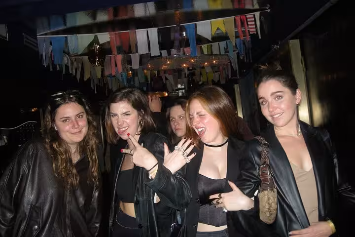 A group of friends posing energetically under colorful flags, embodying the vibrant Barcelona nightlife scene.