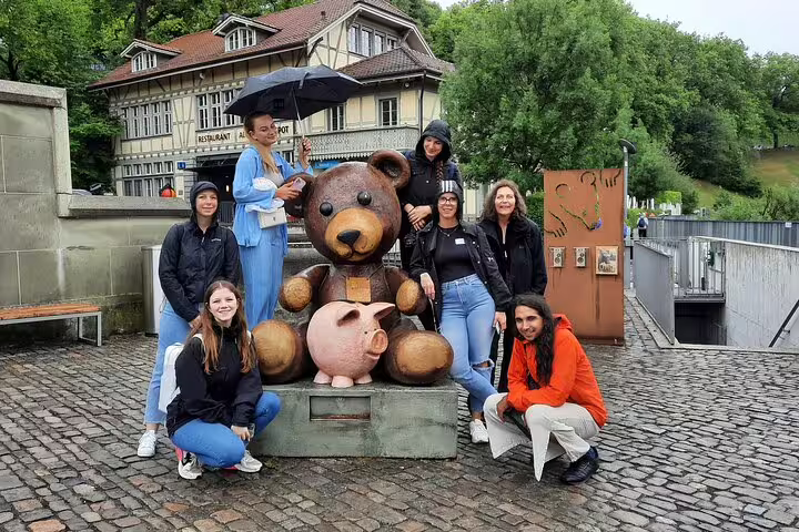 Friends pose by Bern bear statue on a self-guided scavenger hunt tour, exploring Old Town sights