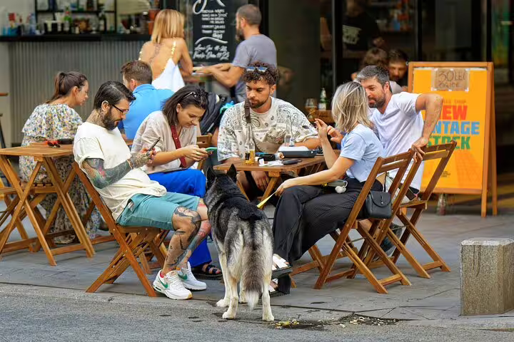 Friends at an outdoor cafe in Bilbao during an e-scavenger hunt, enjoying a self-guided city tour with puzzles