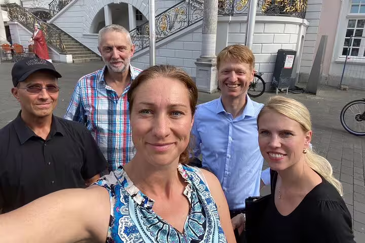 Friends posing in Bonn old town near historic staircase, enjoying a self-guided scavenger hunt walking tour