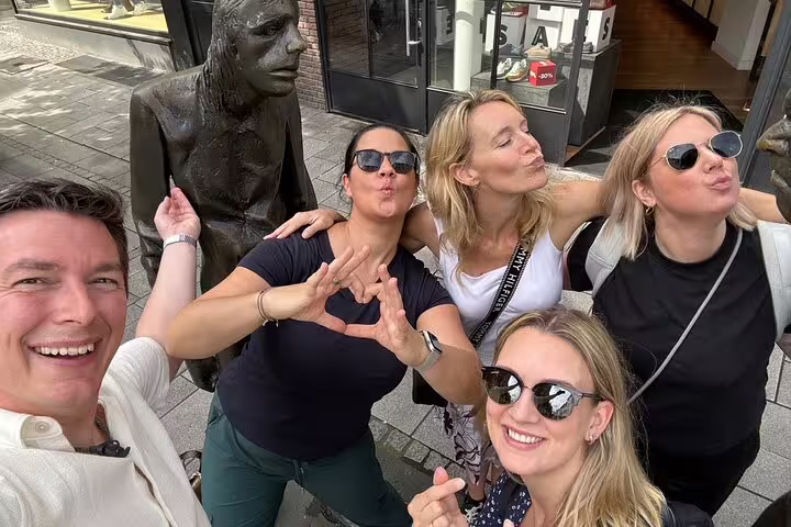 Friends posing by bronze street statue in Düsseldorf on a self-guided scavenger hunt and sights tour