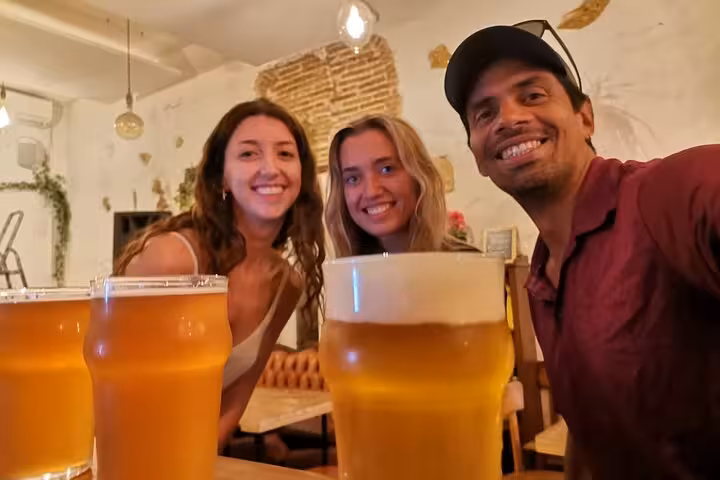 Friends smiling with fresh pints at a Marseille craft beer tasting experience in a cozy local bar