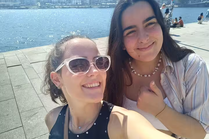 Friends smiling by the Douro River on a Porto scavenger hunt self-guided tour with city sights and puzzles