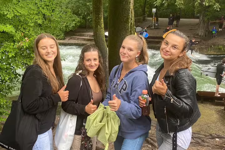 Friends posing by the Eisbach wave in Munich’s English Garden during a self-guided scavenger hunt sightseeing tour