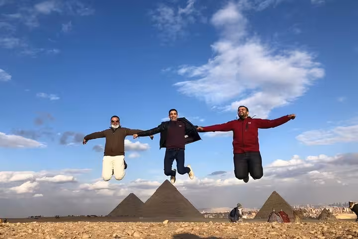 Friends jumping with Giza Pyramids behind on a private Cairo tour with Egyptian Museum and Khan El Khalili