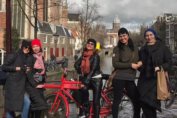 Friends with red bike by Amsterdam canal, private guided bike tour exploring hidden gems and local streets