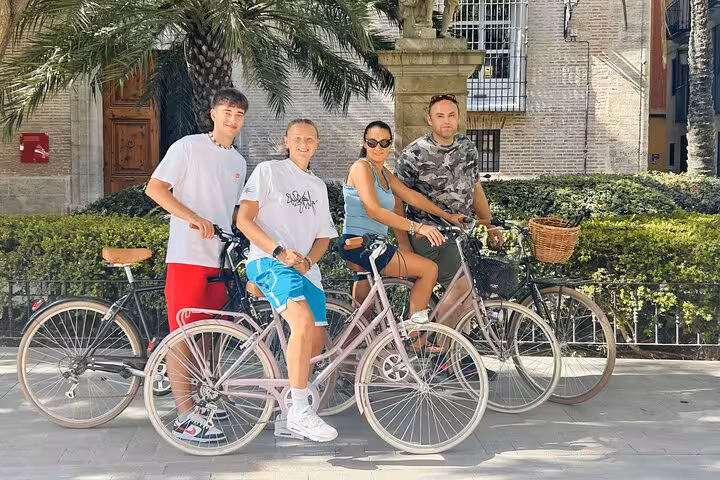 Friends posing with rented adult city bikes in a sunny plaza, perfect for easy city sightseeing by bicycle
