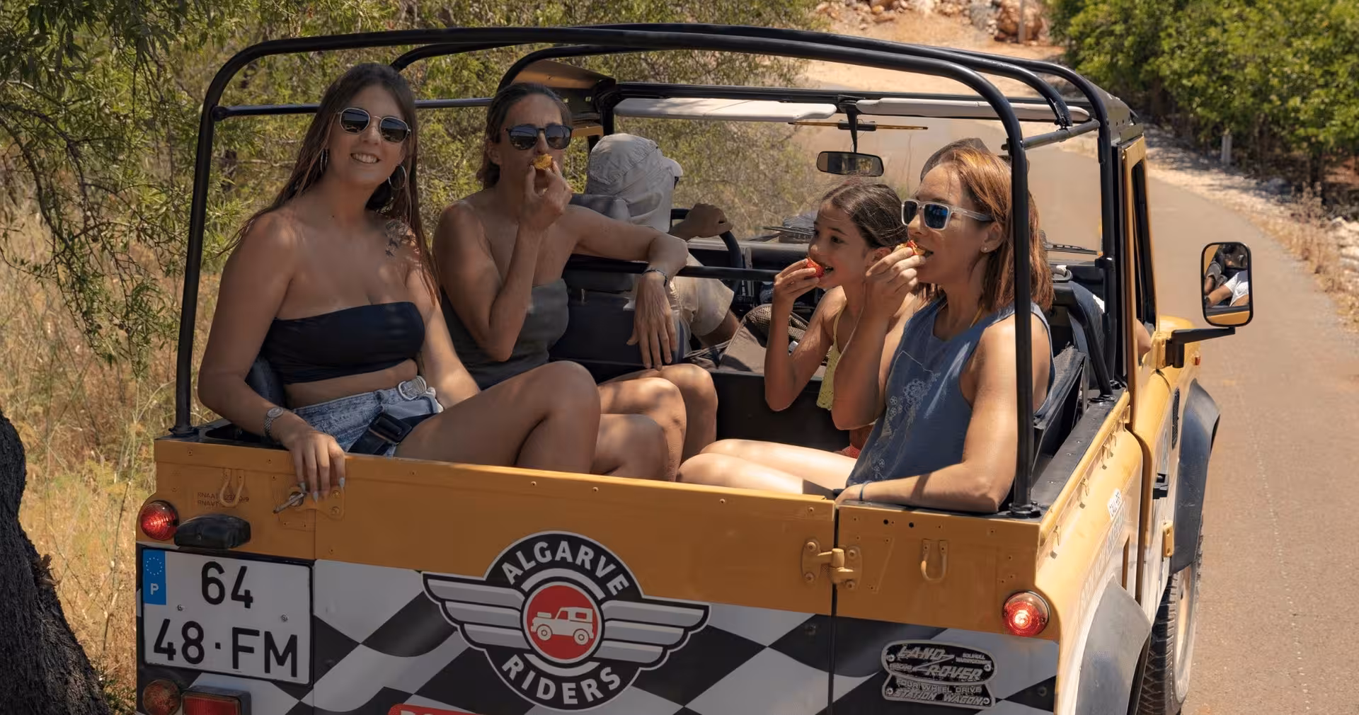 Friends relaxing and eating fruit in an open-top safari jeep during a sunny half-day private Algarve countryside tour