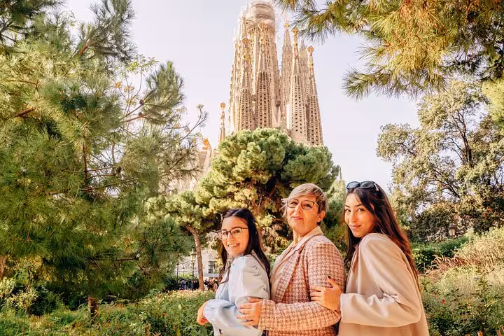 Friends pose in a green park with Sagrada Família backdrop, Timeless Barcelona personal photoshoot in Eixample.