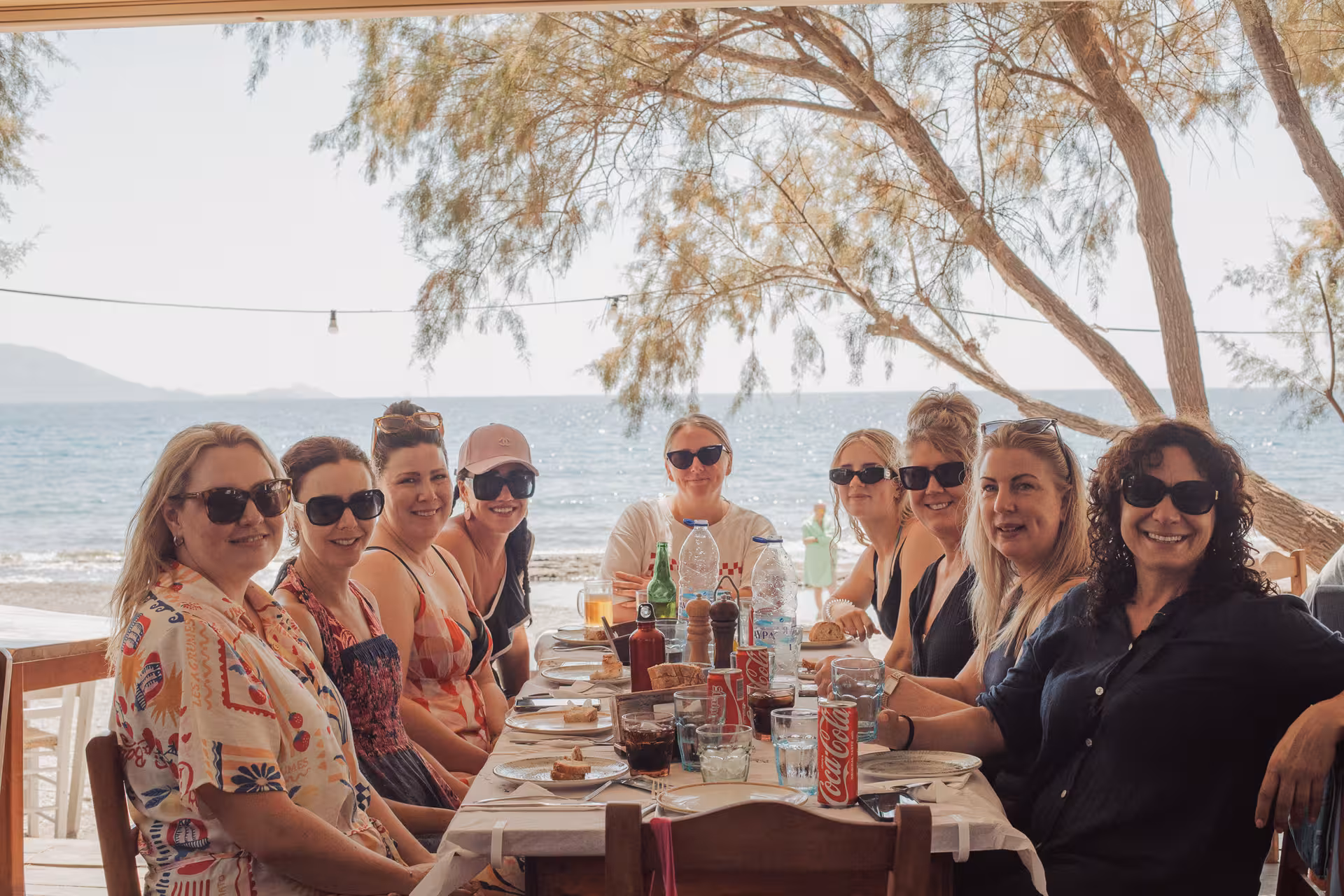 Group of friends enjoy a seaside taverna lunch in Ikaria, savoring Greek cuisine with views of the Aegean on a guided tour