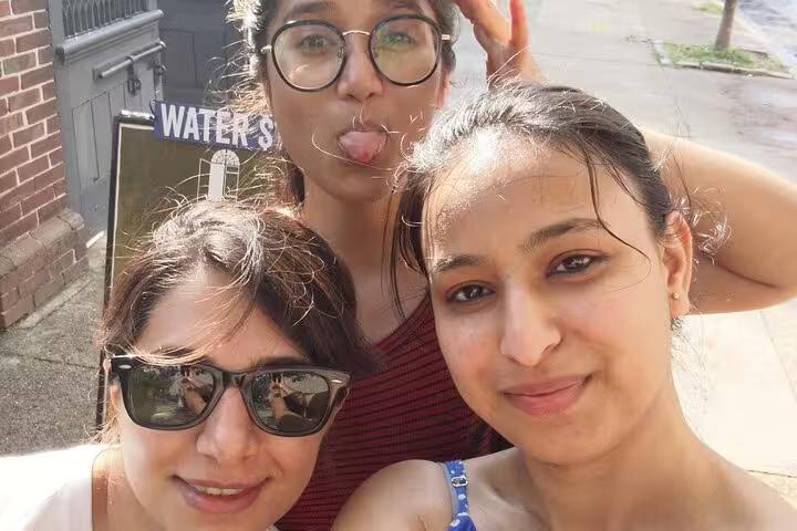 Three women taking a selfie outdoors near a brick building in Old Philadelphia on a sunny day