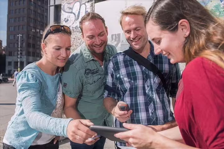Friends using a smartphone for a self-guided e-scavenger hunt in Madrid city center, interactive tour game
