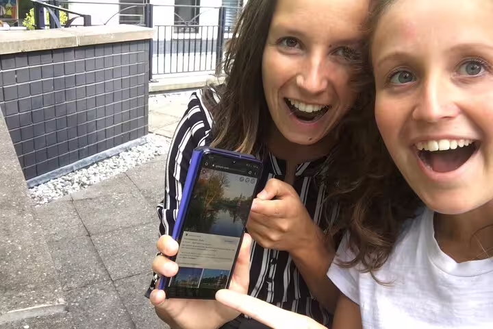 Friends using a smartphone for an e-scavenger hunt in Prague, solving clues and exploring at their own pace