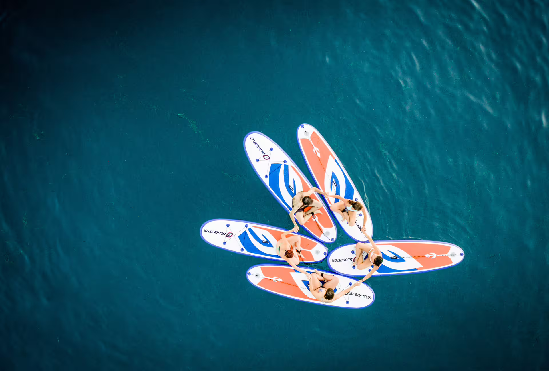 Aerial view of friends on SUP boards forming a circle in turquoise water on a Kardamyli stand up paddle trip