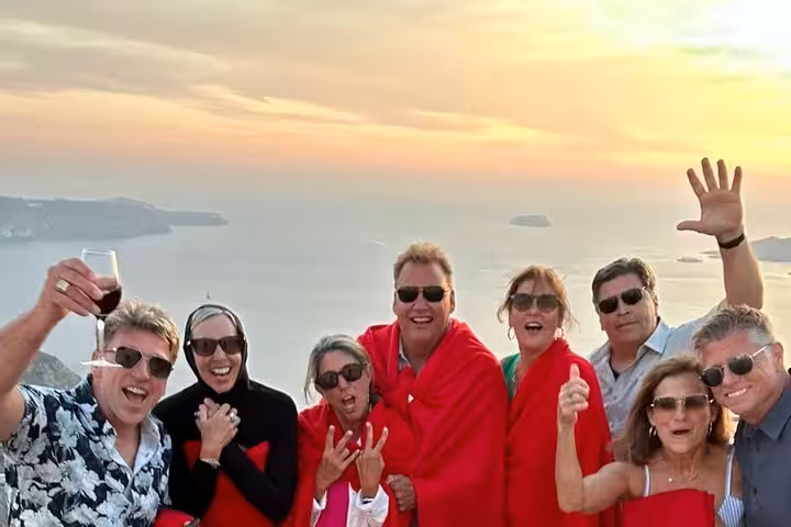 Friends toast red wine at Santorini sunset viewpoint on private 3-winery wine tour with tapas