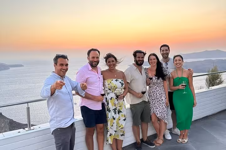 Friends toast wine at Santorini sunset terrace, private wine tour with 3 wineries and tapas tasting experience