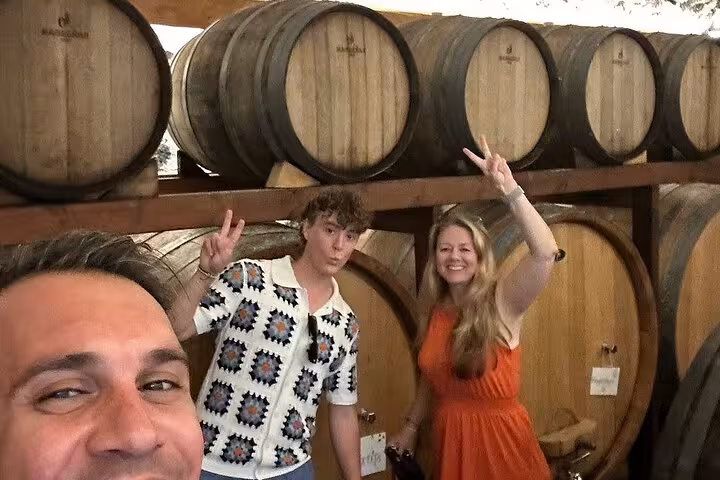 Friends pose in wine cellar beside oak barrels during private wine museum and winery tasting tour