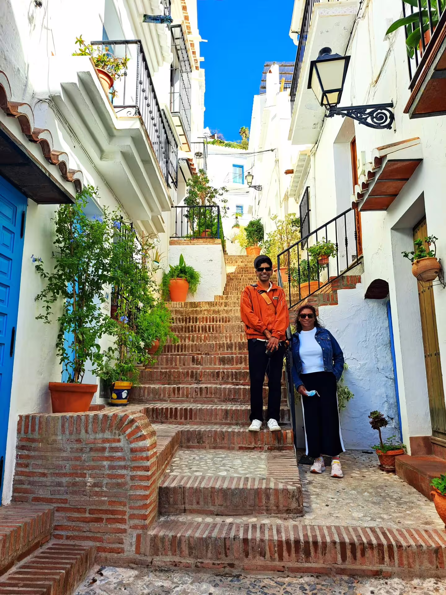Travelers on Frigiliana steps among whitewashed houses and potted plants, private Nerja tour with Marbella pick-up
