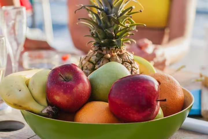 A colorful fruit platter with apples, oranges, and pineapple enjoyed on a private yacht charter.