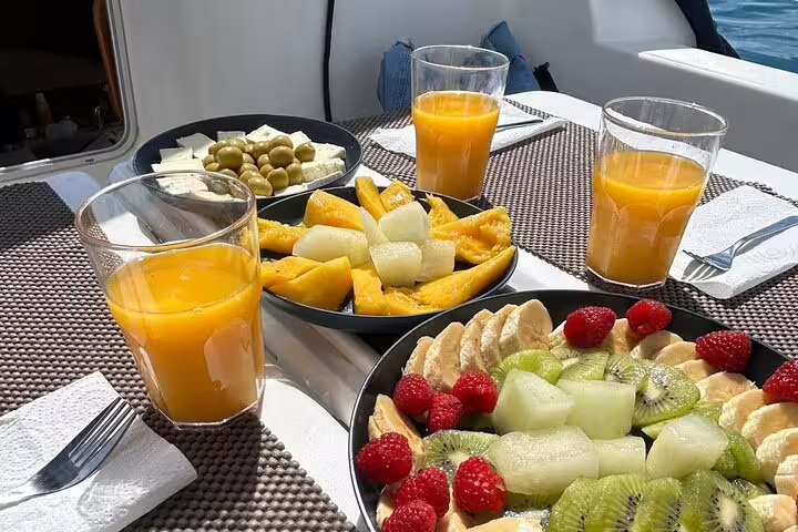 Refreshing fruit platter with juice, melon, kiwi, and berries on a yacht, perfect for Ibiza & Formentera sailing trip.