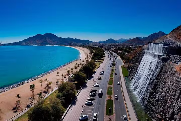 Scenic aerial view of Fujairah coastline with beach and mountain backdrop, ideal for exploring nature and heritage.