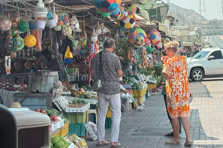 Friday Market stop on Fujairah City and Khorfakkan tour, shoppers browsing fruit and souvenir stalls