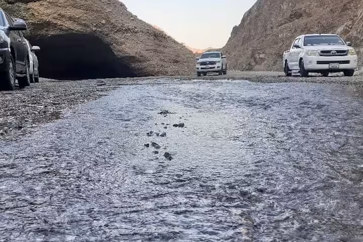 4x4 vehicles crossing a wadi stream in rocky mountains on Fujairah Khorfakkan safari tour