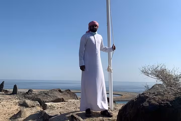 Local Emirati guide at Khorfakkan coastal viewpoint on Fujairah City tour with sea and mountains backdrop