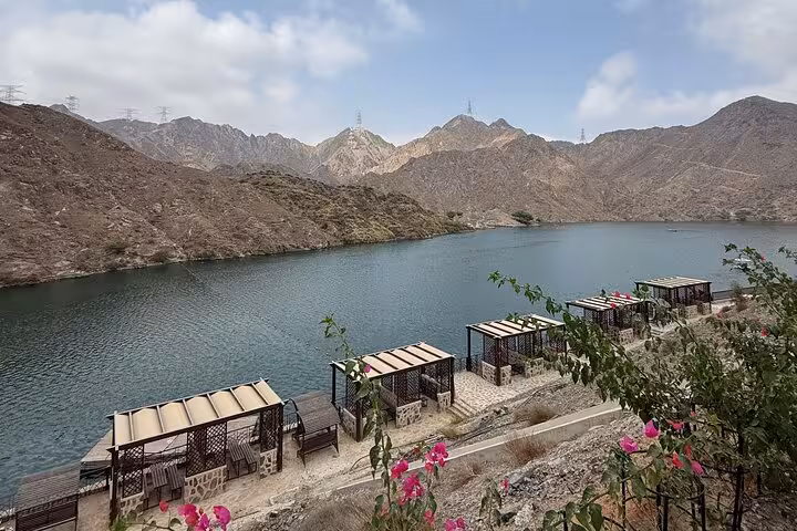 Scenic Fujairah dam lake viewpoint on Khorfakkan tour with mountain backdrop and shaded picnic huts