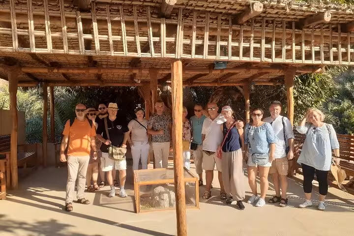 Tour group at traditional palm shelter stop on Fujairah Khorfakkan mountains safari sightseeing tour UAE