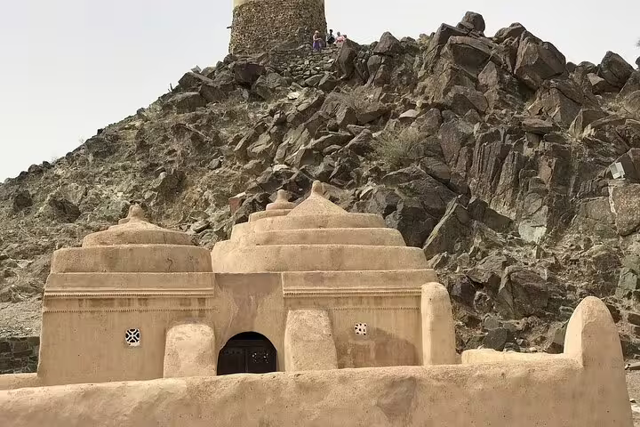 Historical mud-brick mosque nestled against rocky terrain in Fujairah, showcasing cultural heritage and architecture.