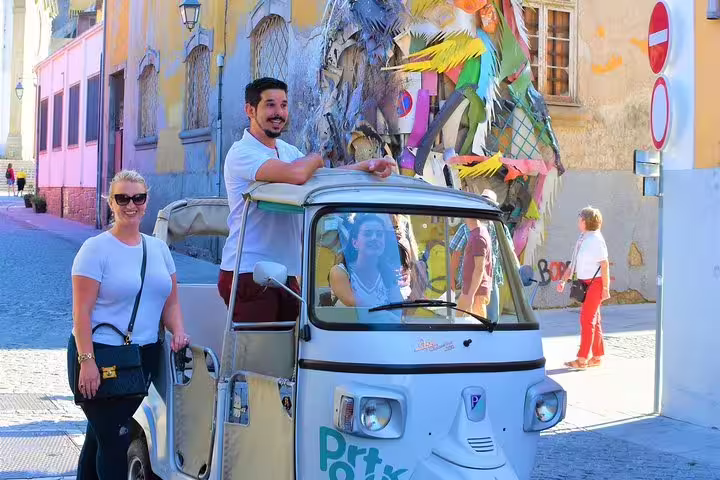 Tourists enjoy a vibrant tuk tuk ride through Porto's colorful streets, exploring local art and culture on a full-day private tour.