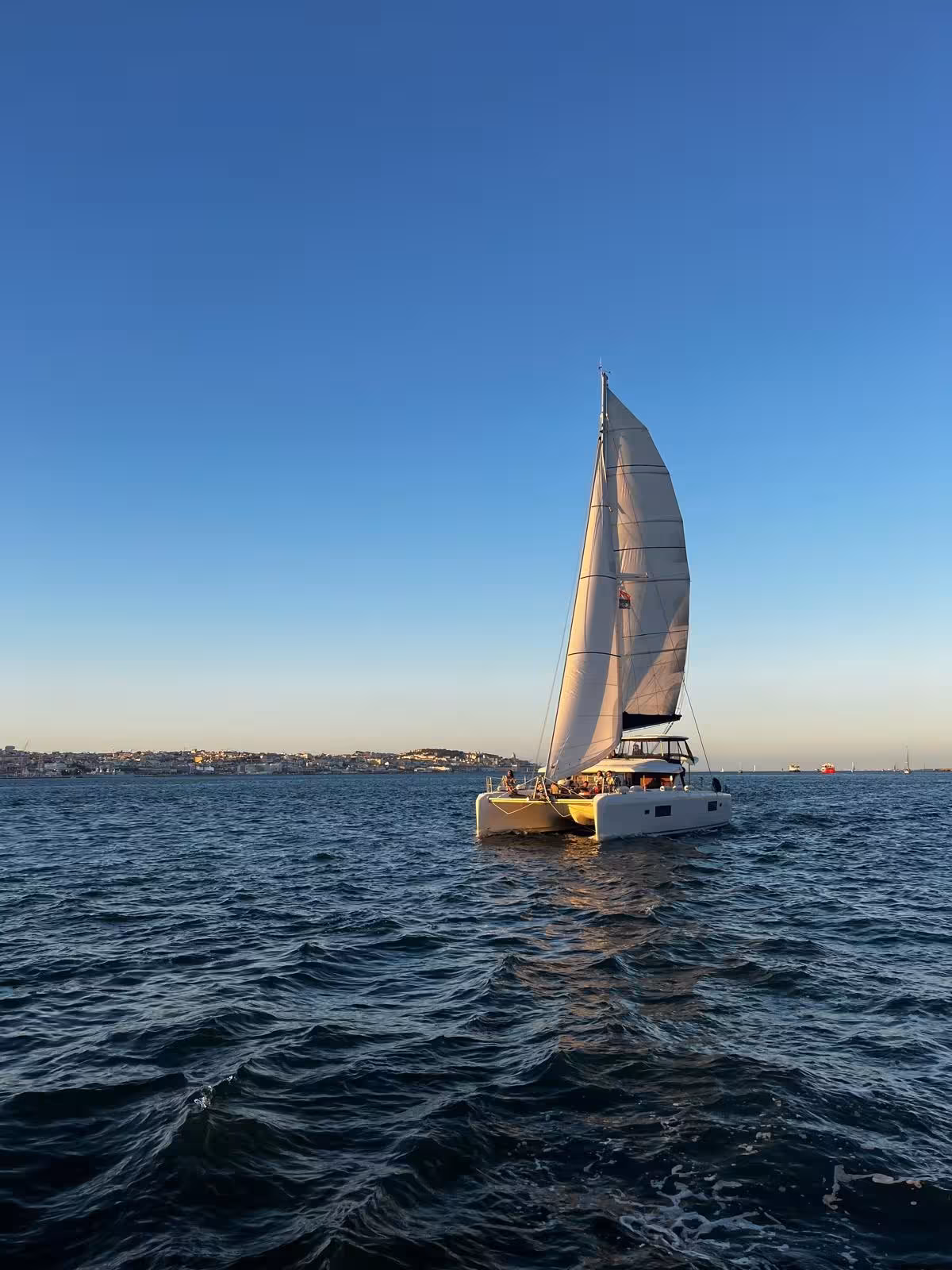 VIP catamaran sailing at sunset on Fun & Swim tour, open sea views and coastal skyline in the distance