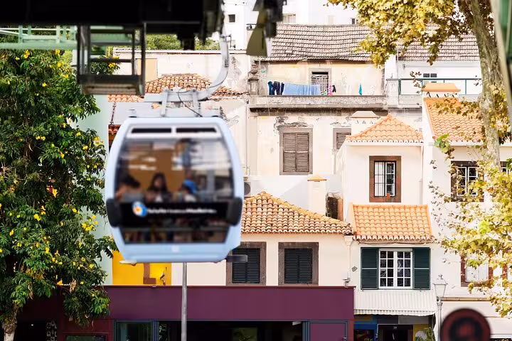 Cable car glides over colorful rooftops in Funchal, offering a unique perspective of the cityscape.