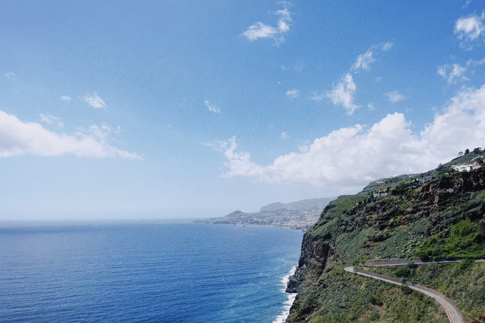 Scenic coastal view of the Atlantic Ocean and lush cliffs along the e-bike road tour route from Funchal to Garajau, Madeira.