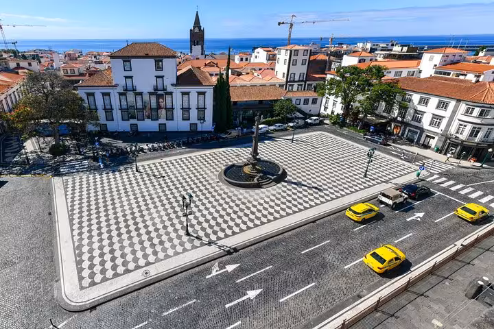 Aerial view of Funchal's historic square with patterned pavement, surrounded by charming architecture and bustling streets.