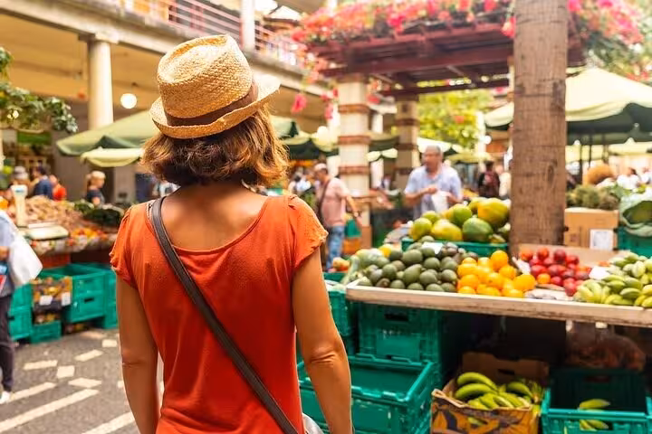 Visitor exploring vibrant Funchal market stalls with fresh local produce during a private guided city walk.
