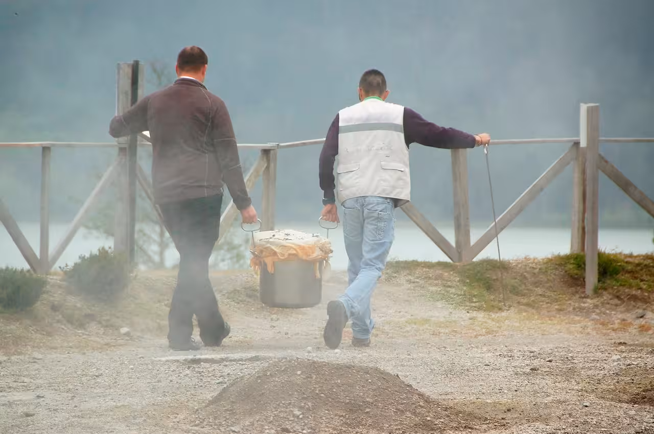 Local guides carry a steaming pot of traditional Furnas cozido from geothermal ground on a full-day Azores Jeep tour