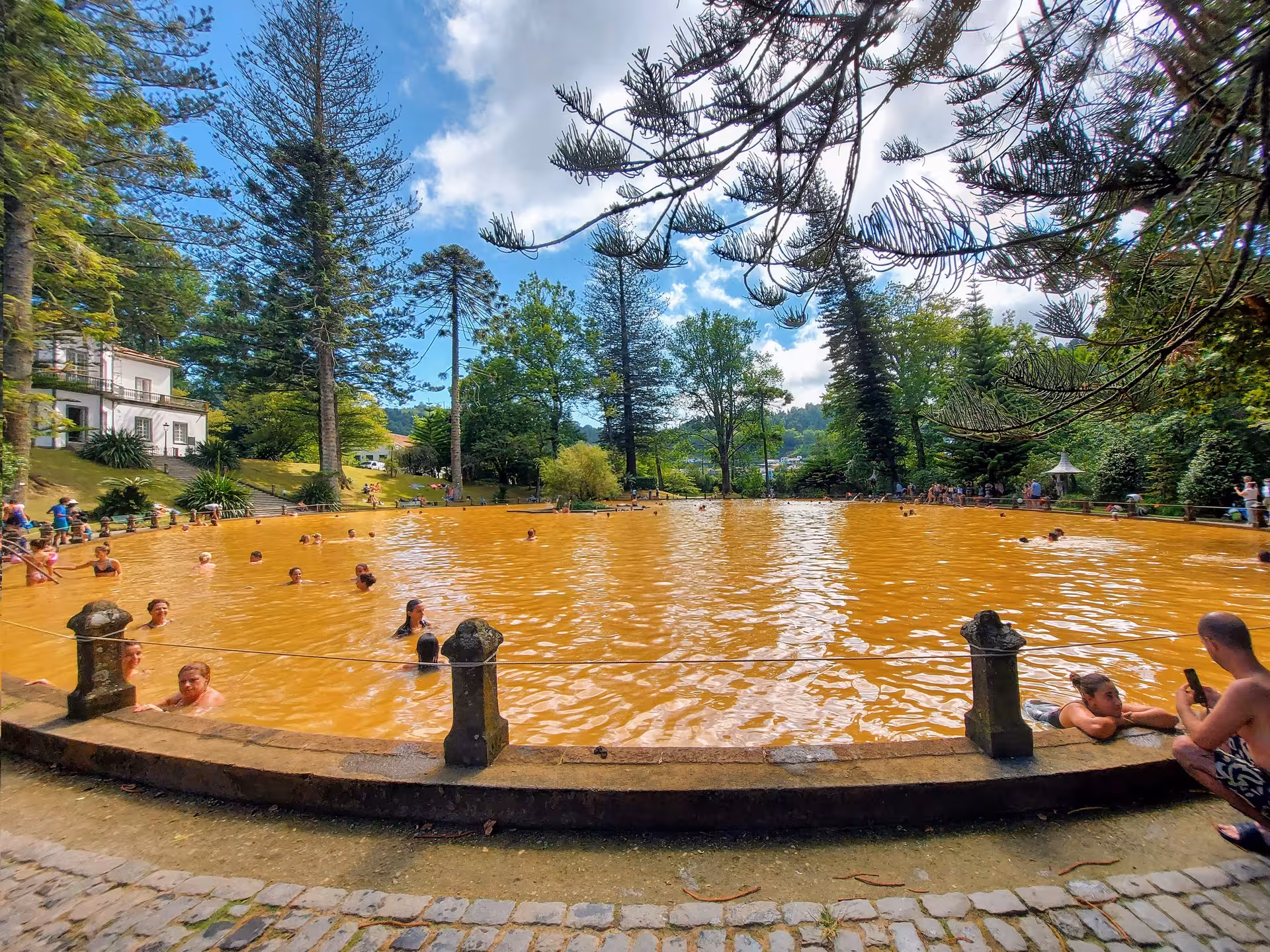 Travelers bathe in the iconic orange geothermal pool at Terra Nostra Garden in Furnas, São Miguel, Azores