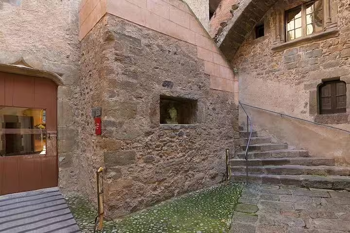 Historic stone courtyard at Gala Castle featuring rustic steps and arched windows, perfect for exploration.