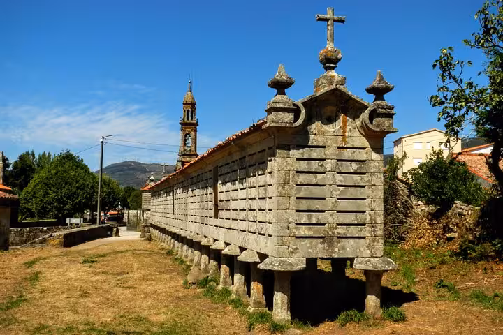 Traditional Galician granary with scenic church backdrop, featured in the North of Spain and Portugal tour.