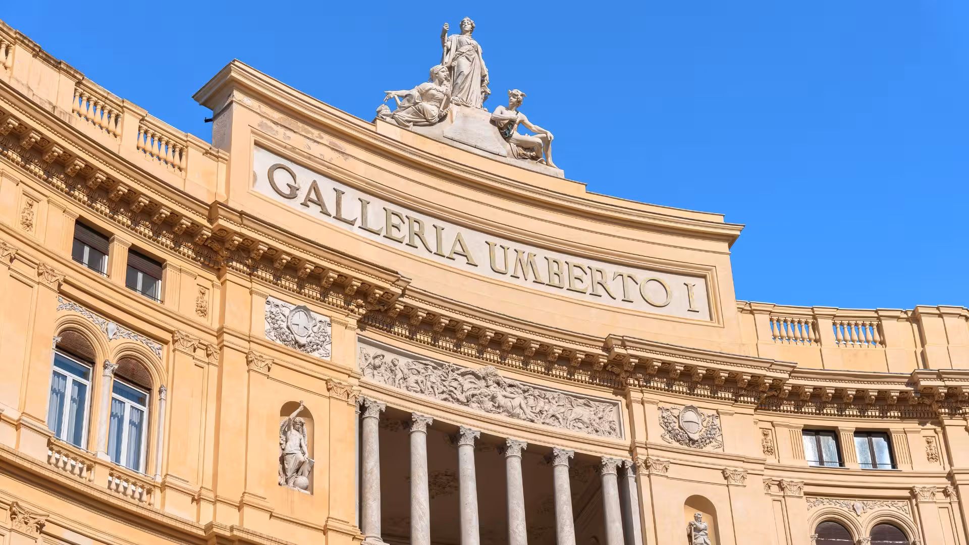 Historic Galleria Umberto I in Naples, showcasing elegant architecture and cultural heritage under a clear blue sky.