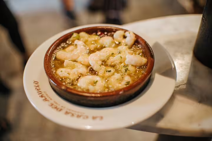 Savor delicious Spanish gambas al ajillo served in a traditional clay dish on the Tapas Tour Madrid Experience, perfect for food lovers.