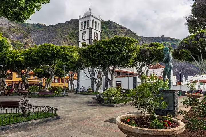 Charming plaza with lush trees and a historic tower in Garachico, Tenerife, showcasing cultural heritage and natural beauty.