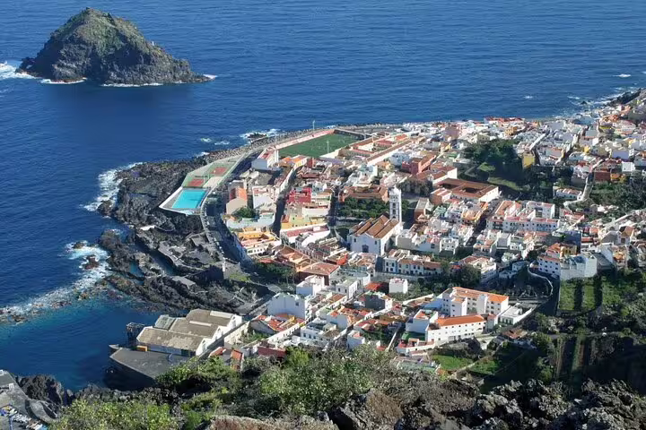 Aerial view of Garachico, Tenerife, showcasing colorful buildings and coastline against the blue Atlantic Ocean.