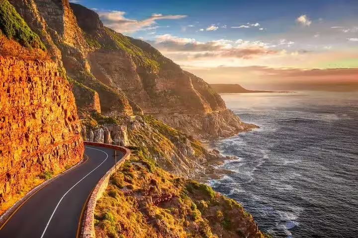 Scenic coastal drive along Africa’s Garden Route with breathtaking ocean views and rugged cliffs at sunset.