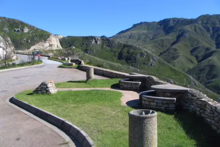 Breathtaking mountain pass along the Garden Route in Africa with winding road and stone picnic areas on a sunny day.