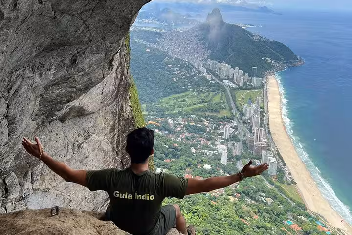 Hiker enjoying panoramic views from Garganta do Céu, Pedra da Gávea, overlooking Rio's coastline and lush landscape.