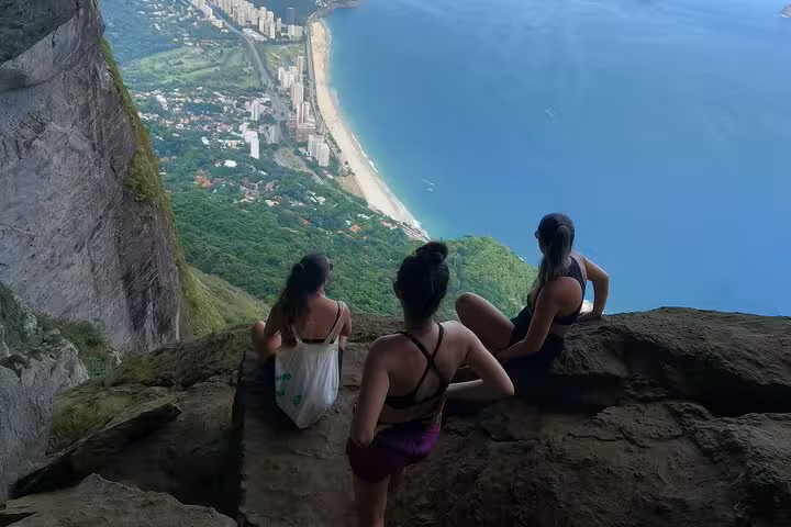 Hikers admire breathtaking views from Garganta do Céu, overlooking the stunning coastline below in Pedra da Gávea.