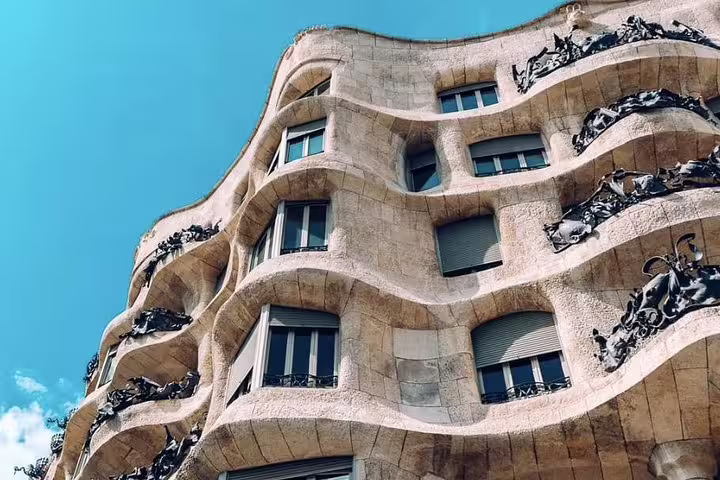 Stunning facade of Gaudi's Casa Milà in Barcelona, showcasing its unique curves and intricate ironwork under a clear sky.
